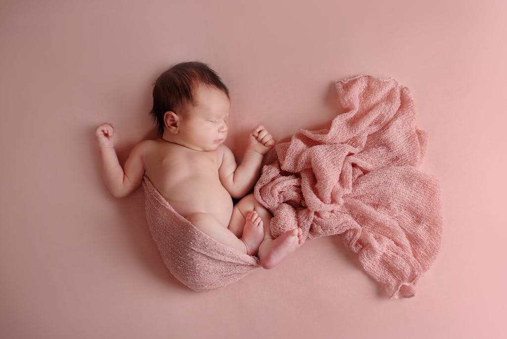 Adorable newborn baby peacefully sleeping wrapped in a soft pink blanket, highlighting serenity and innocence.