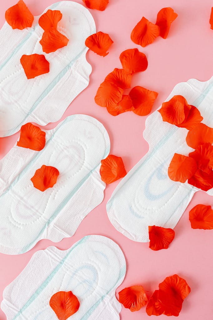 Artistic composition of sanitary pads and red petals symbolizing menstrual cycle. Ideal for health and wellness themes.