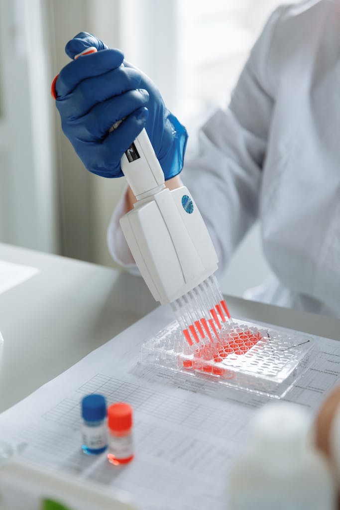 Close-up of a scientist using a pipette for laboratory research with red samples.